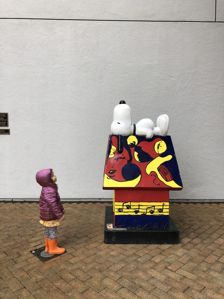 child looking at snoopy on his house outside of the Charles Shulz Museum in Santa Rosa California