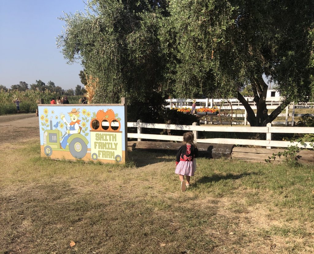 child running towards sign that says "smith family farms"