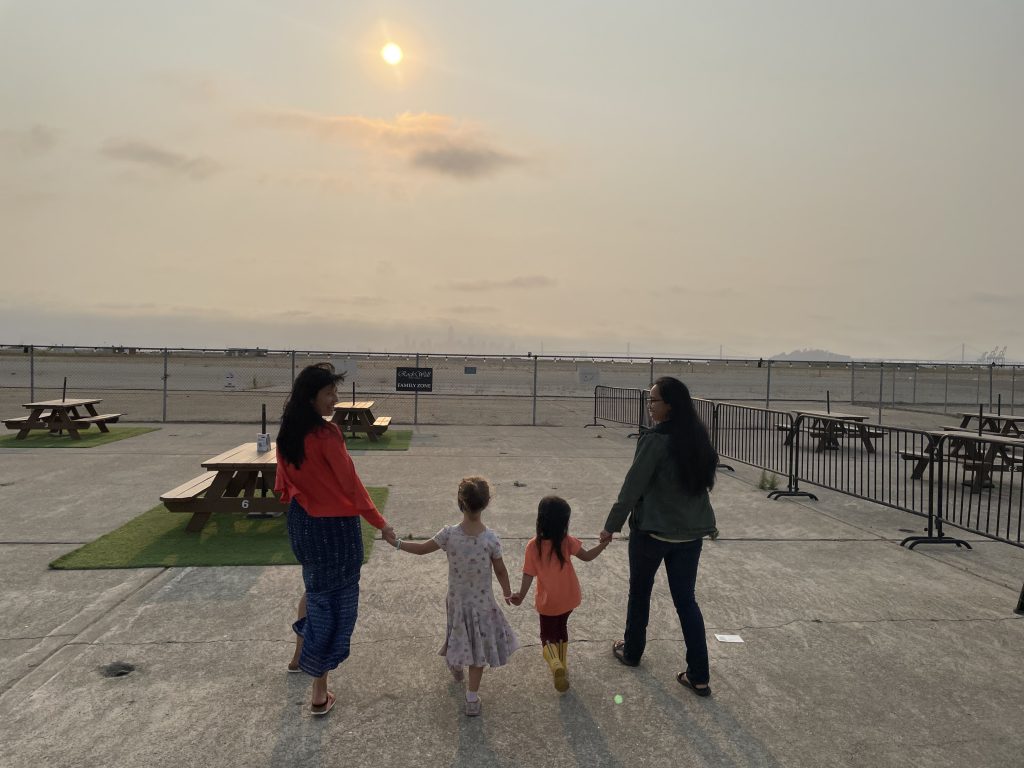 Angel and Jelly hold hands with each of their children as they walk towards the sunset.