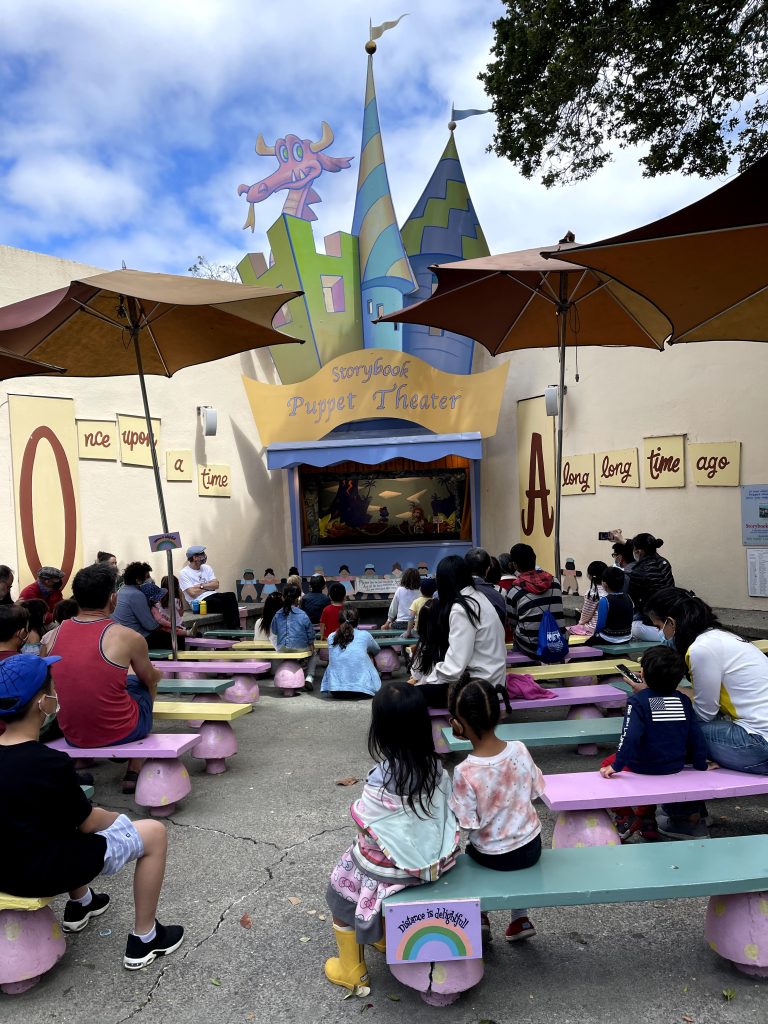 Children and adults watch the puppet show at Fairyland.