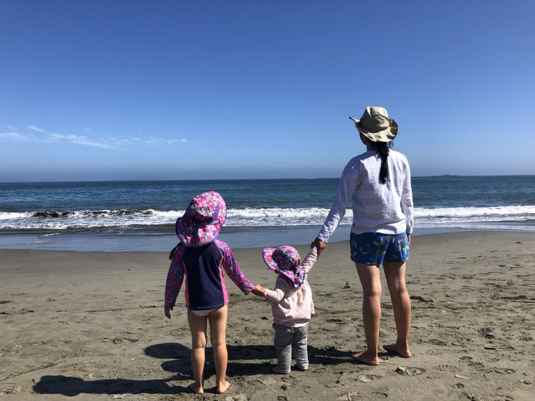 adult and two children looking at the ocean on the beach