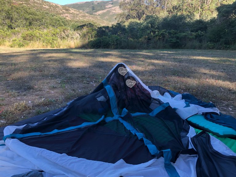 Two children inside of a collapsed camping tent