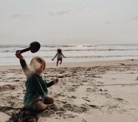 child throwing sand on the beach