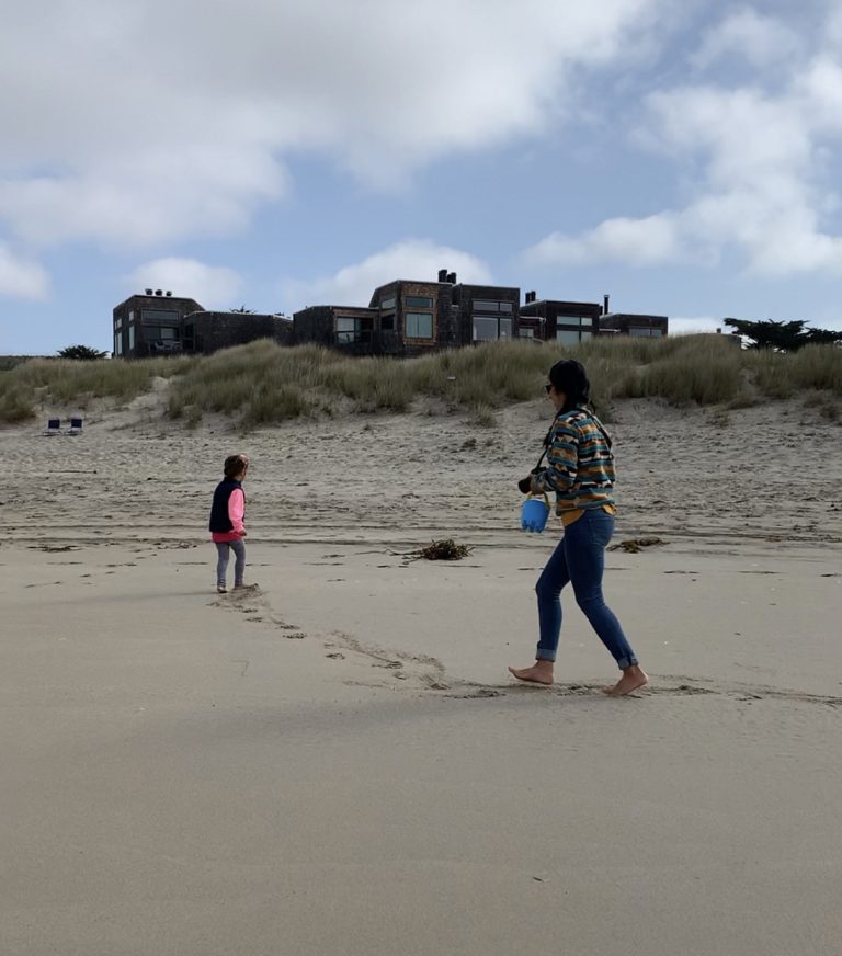 adult and child playing on the beach with condos in the background