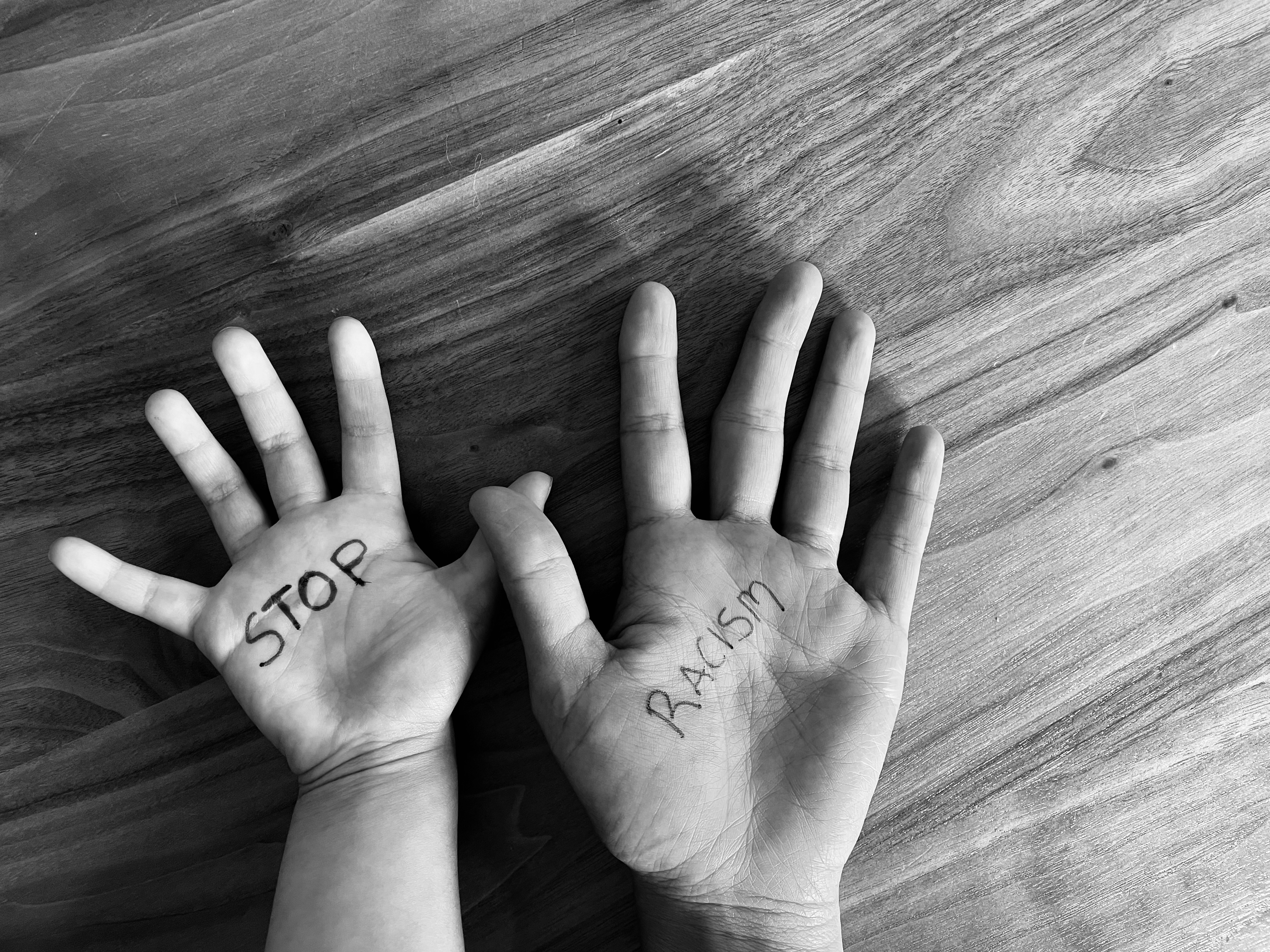 child hand and adult hand with "stop racism" written on the palms