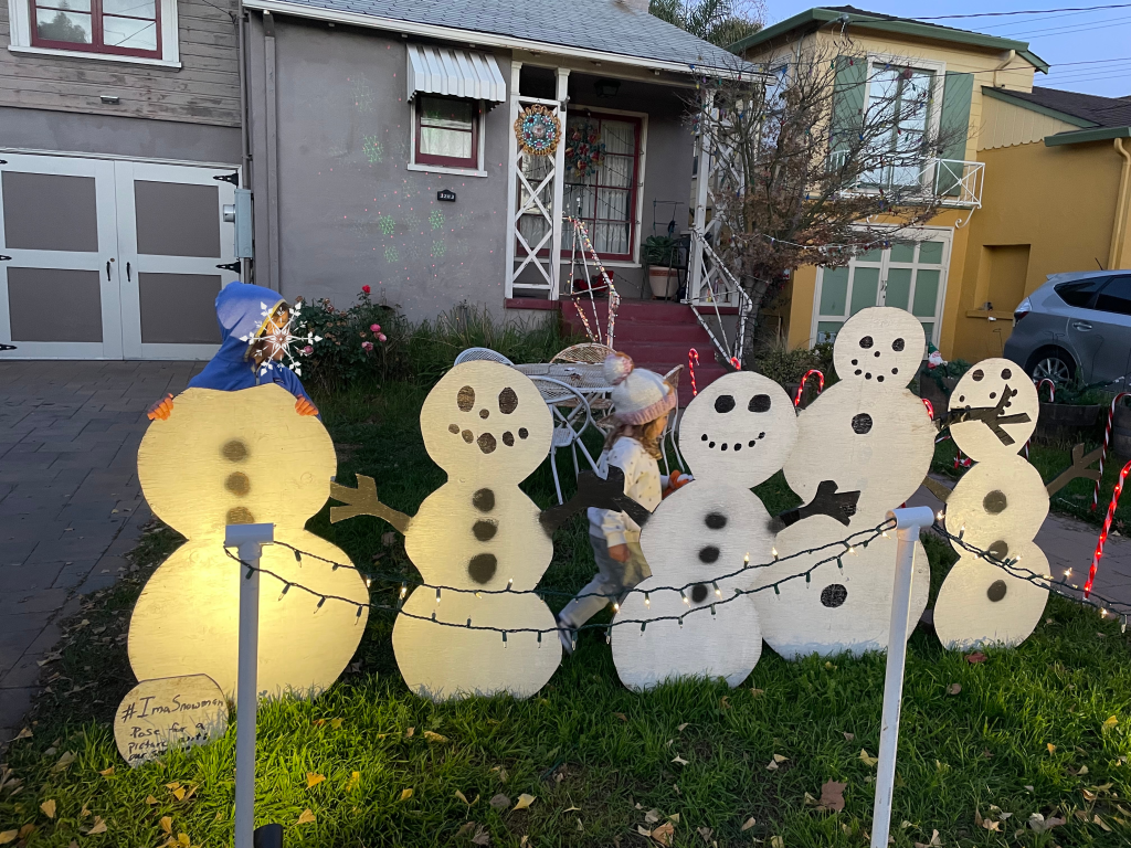 children behind wooden snowman cutouts