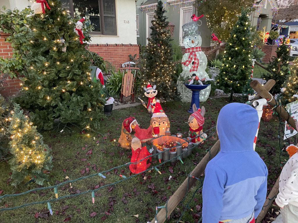 Child looking at light up animals around a campfire at Christmas Tree Lane in Alameda California