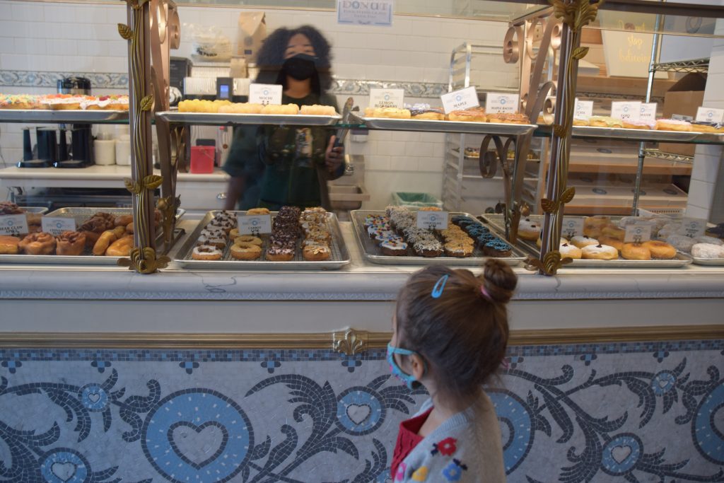 child looking at a display of donuts