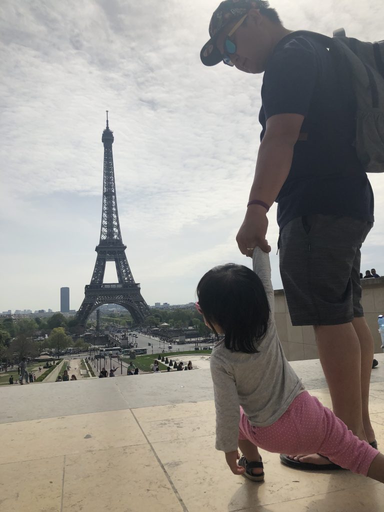 A child and her father look out to the Eiffel Tower from Trocadero.
