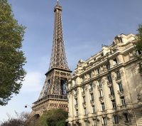 The Eiffel Tower looms behind a neutral colored building.