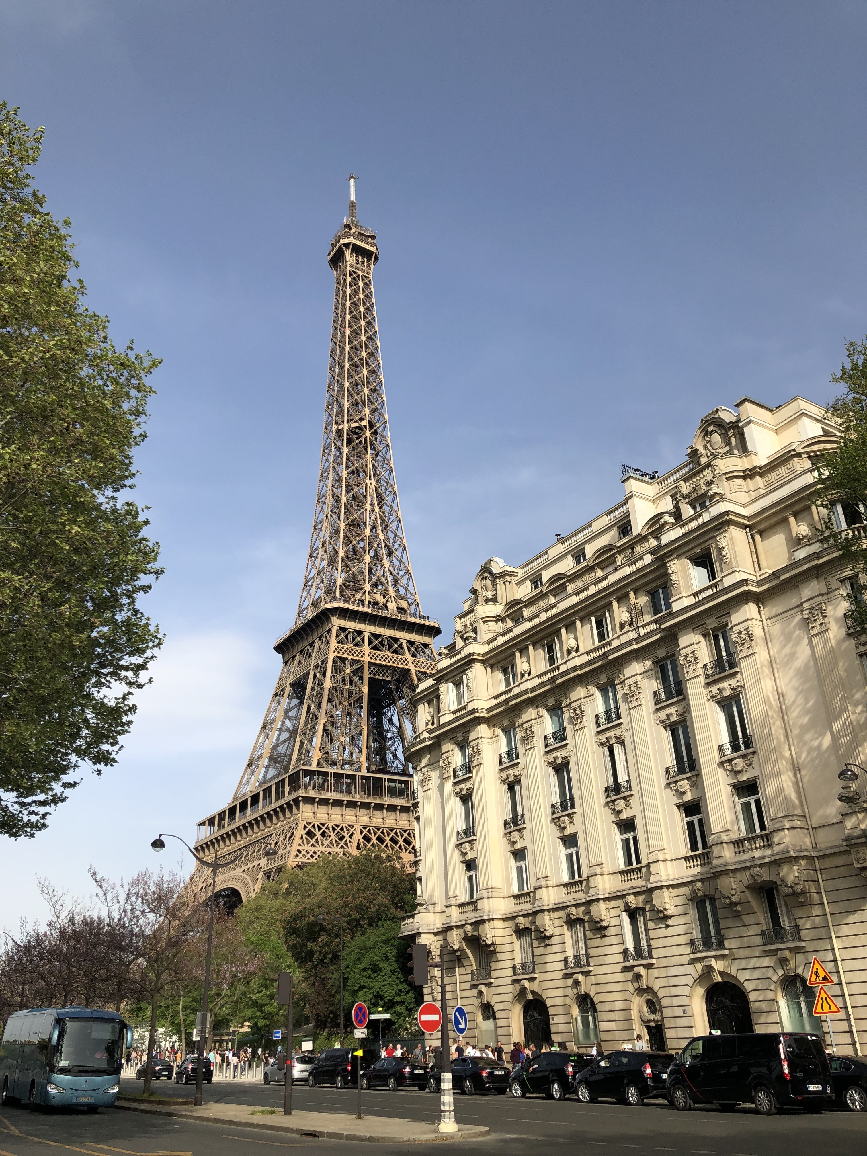 The Eiffel Tower looms behind a neutral colored building.