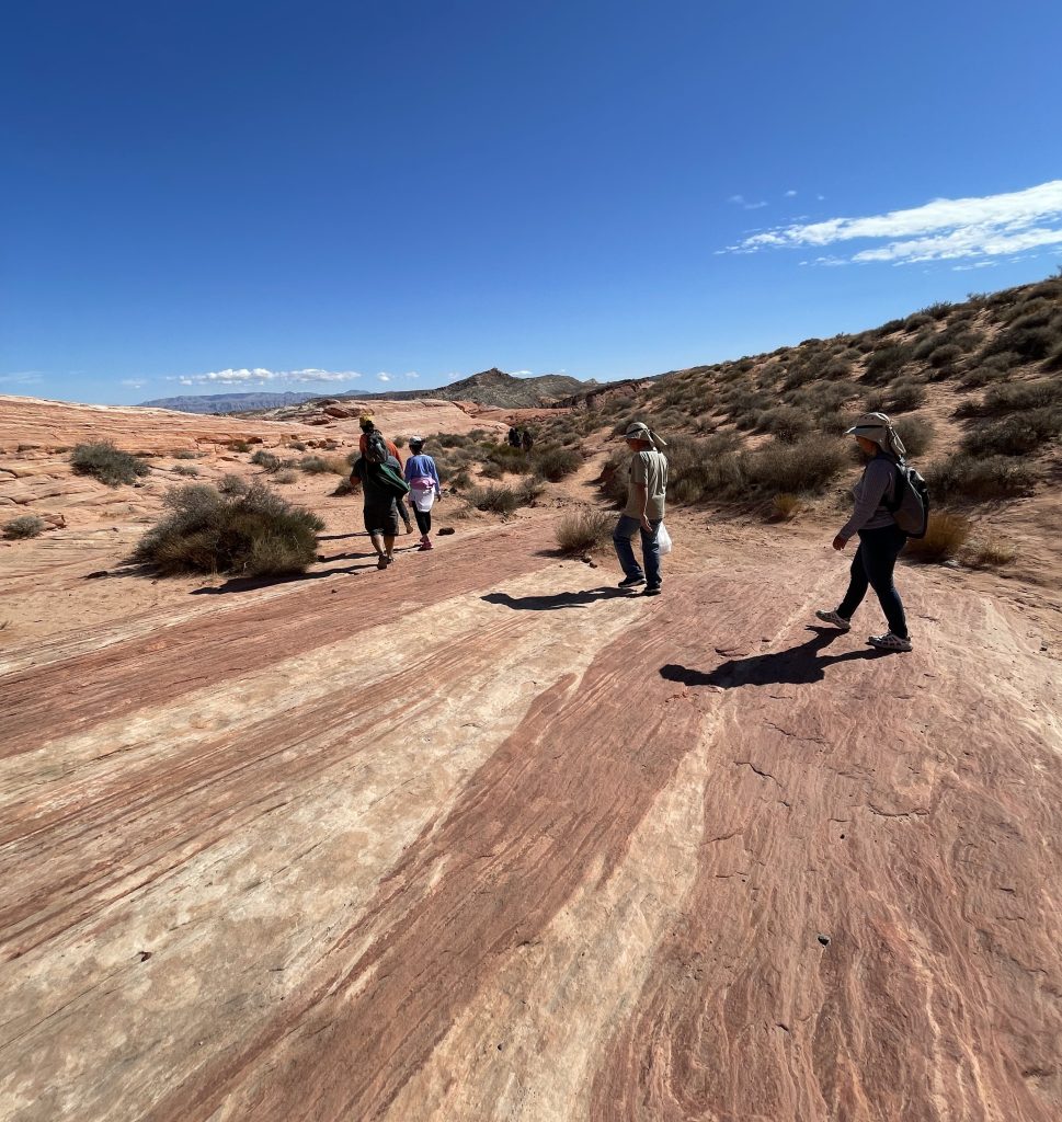 A group hikes across the red rock in Valley of Fire State Park.