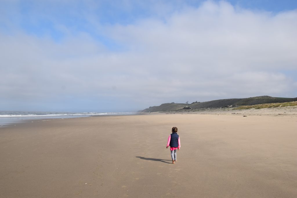 A child a walking down Palm State Beach in Watsonville California