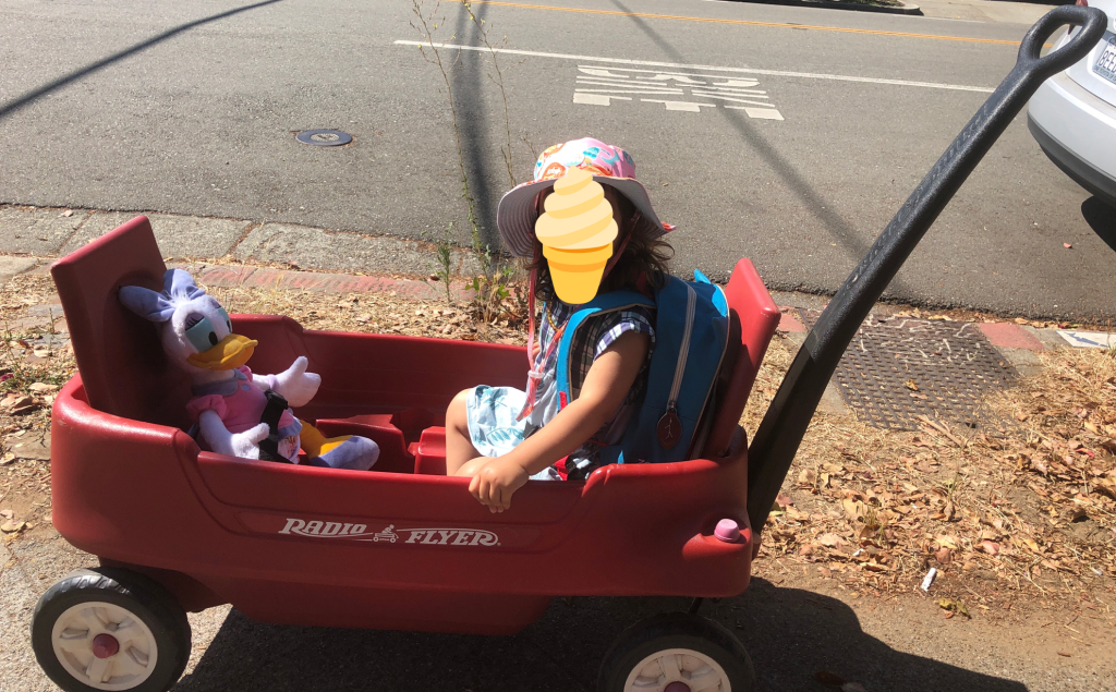 A child sitting in a Radio Flyer wagon with a Daisy Duck stuffed animal at the Santa Cruz Beach Boardwalk