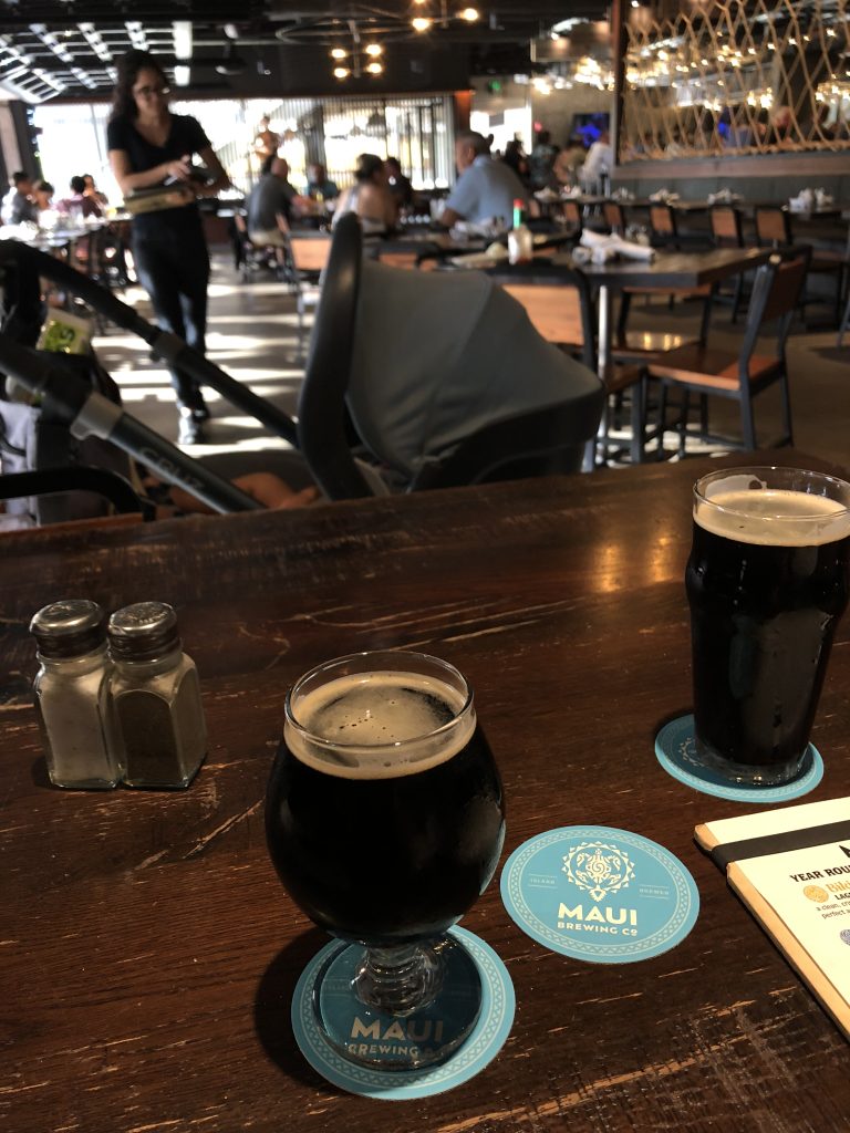 Two dark beers sit atop a table in a restaurant.