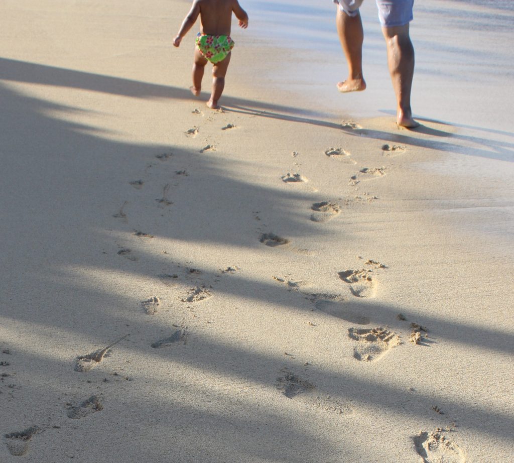 Two sets of footprints can be seen in the sand--a child's and her father's.