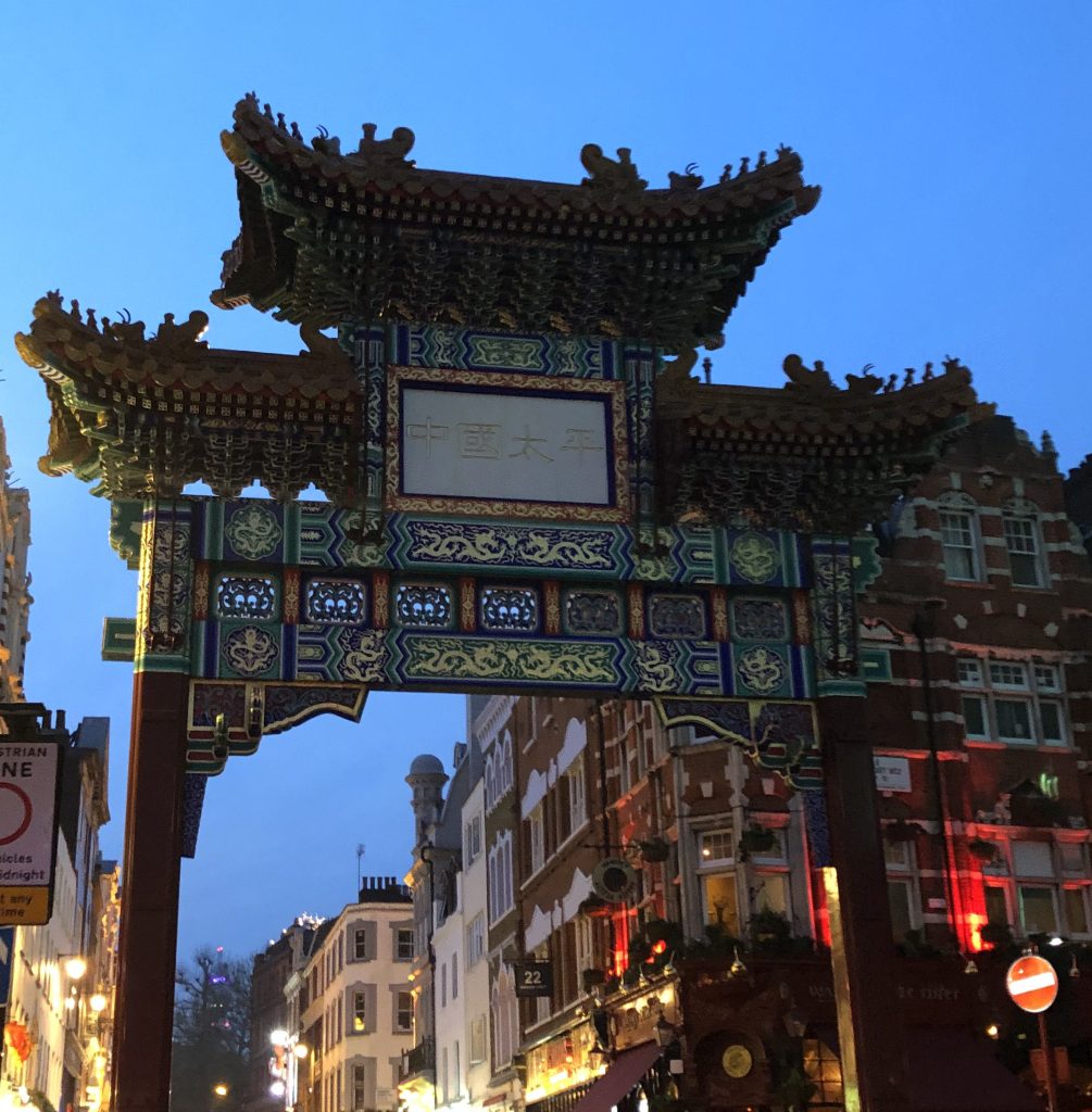 London's green and gold-embossed chinatown gate stands tall in the dusk London sky.