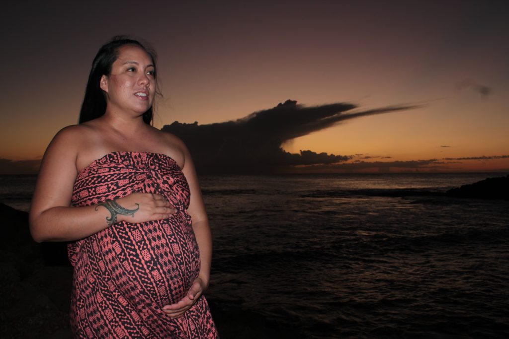 Pregnant person with a sunset in hawaii