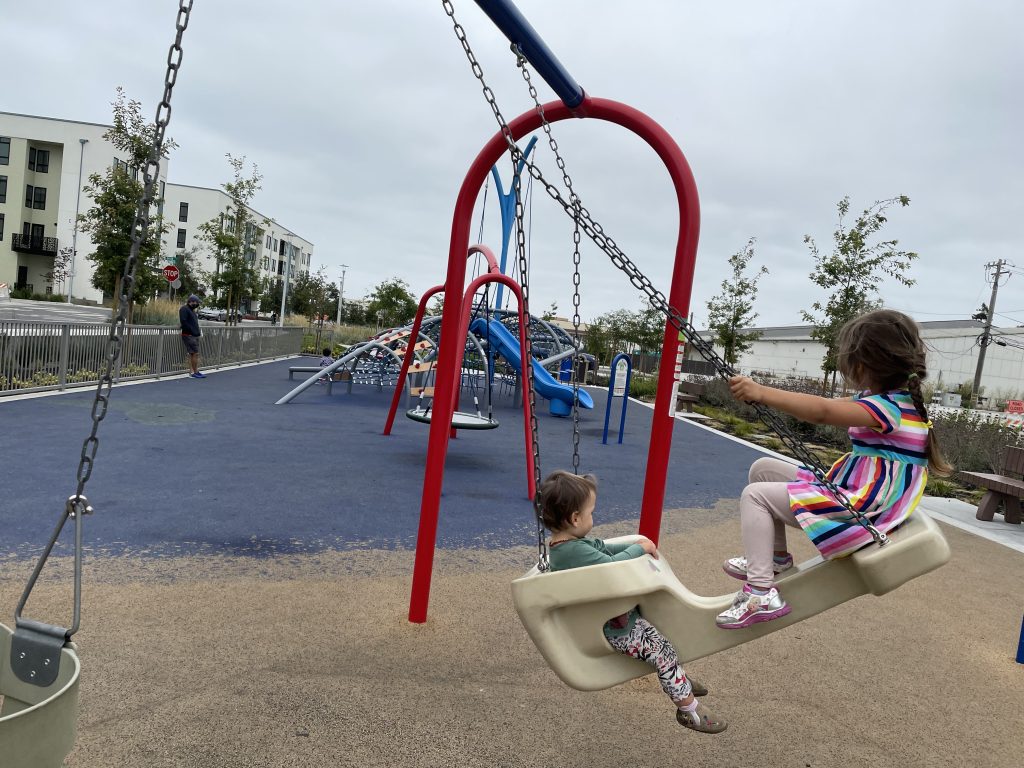 Two children on a swing at a playground at Alameda Point