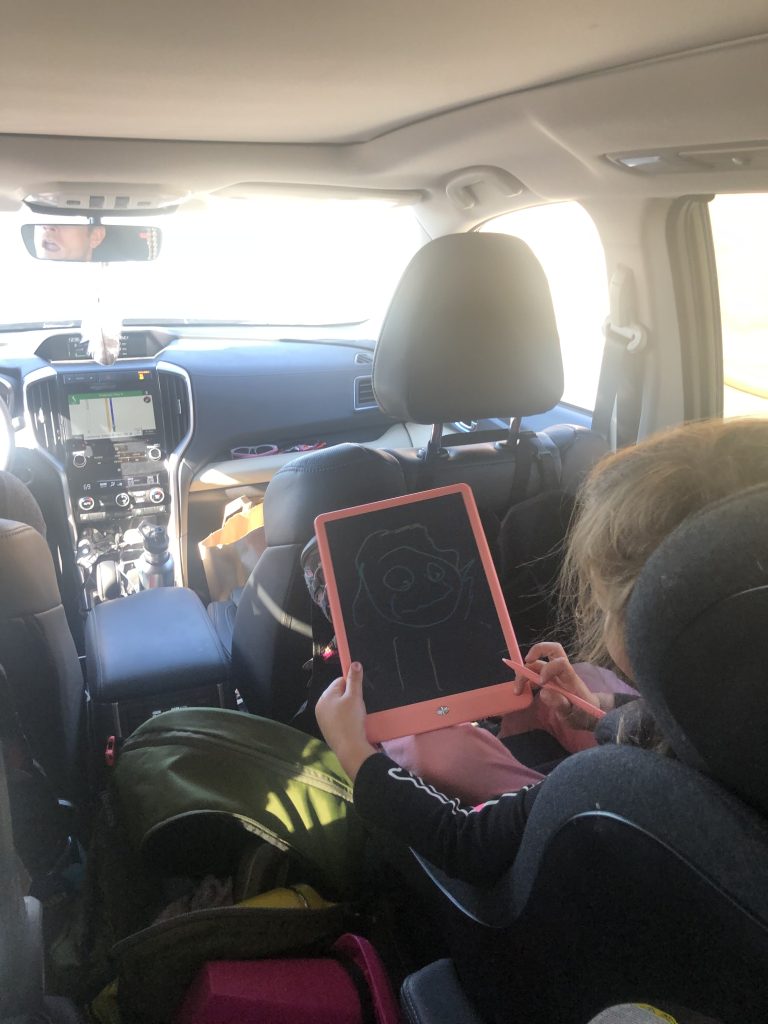 A child in her carseat draws a picture.
