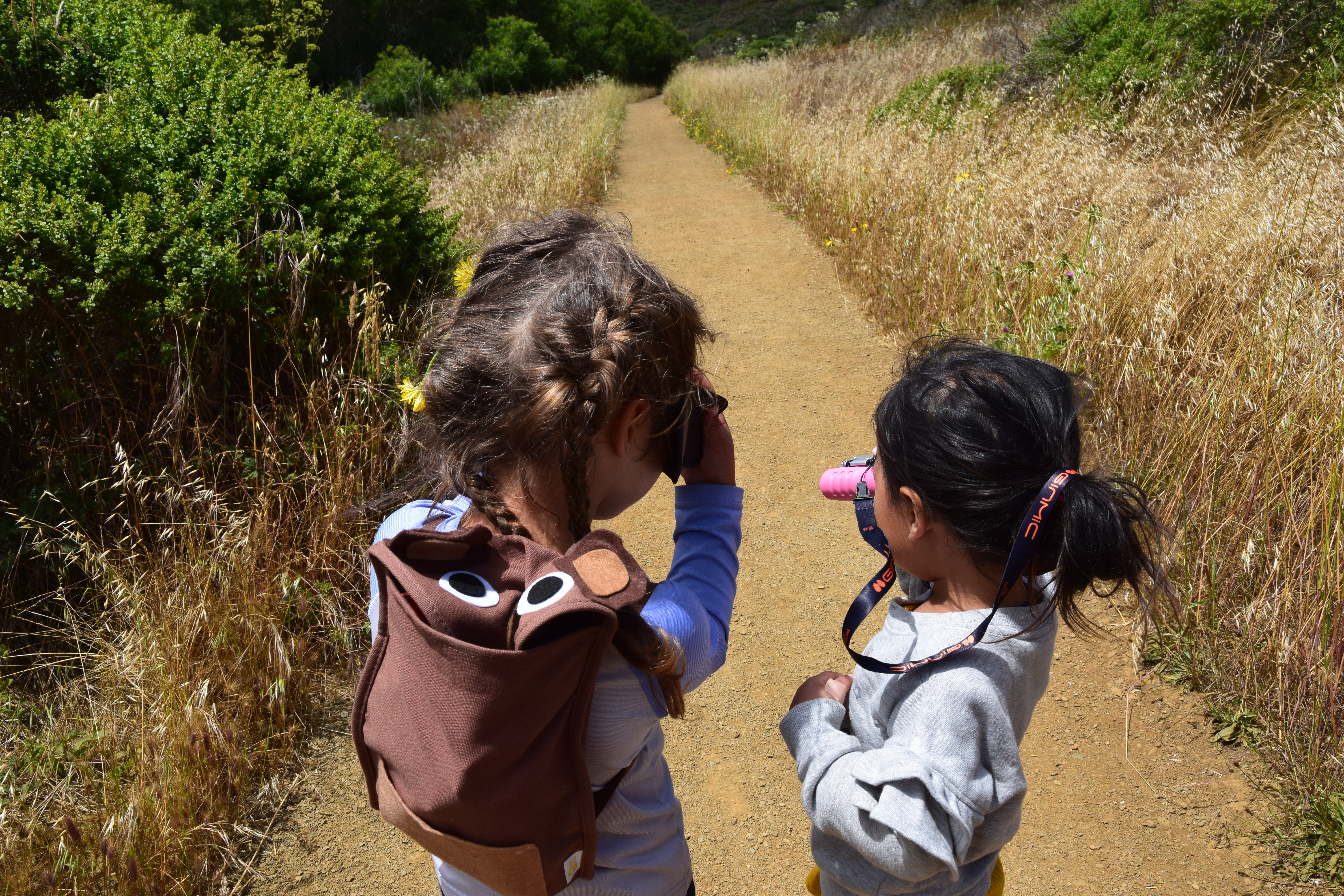 Two children looking through binoculars on the Tennessee Valley Trail while hiking