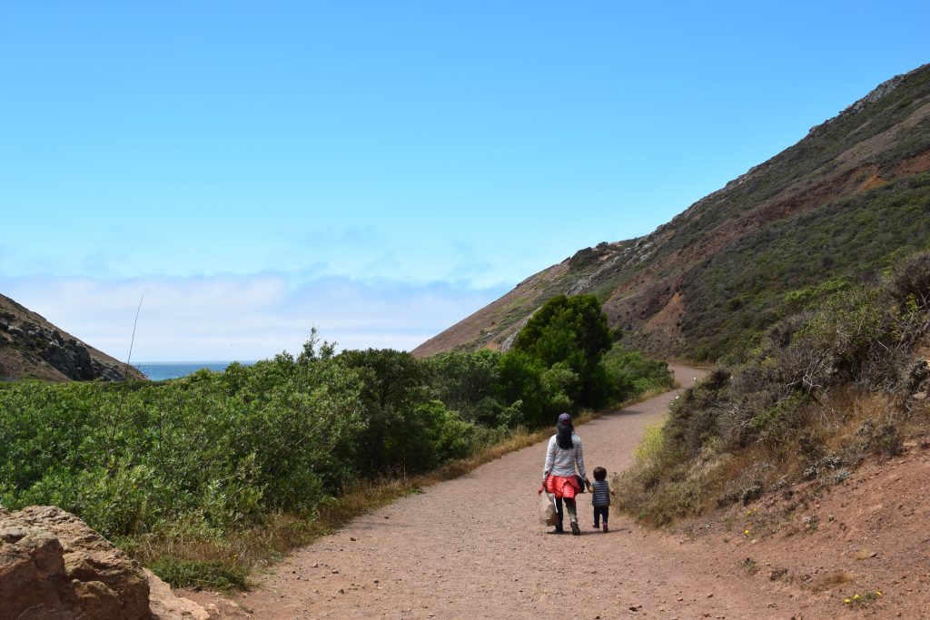 parent and child hike towards a beach cove