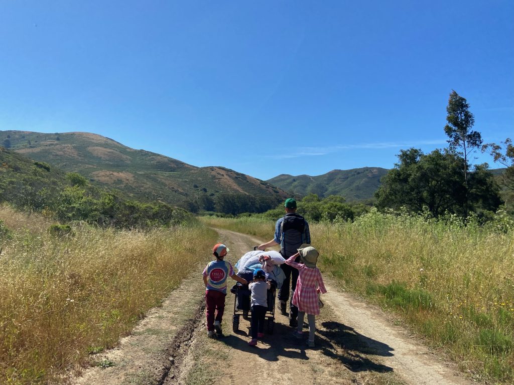 An adult pulling a wagon along the trail to Haypress Campground in Tennessee Valley, Mill Valley, California, with kids