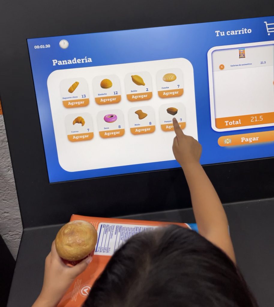 A child points to an item on a grocery check-out screen.