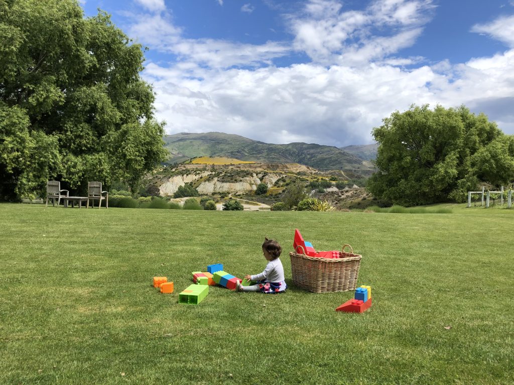 Child at a winery in Otago, New Zealand playing with toys on the grass