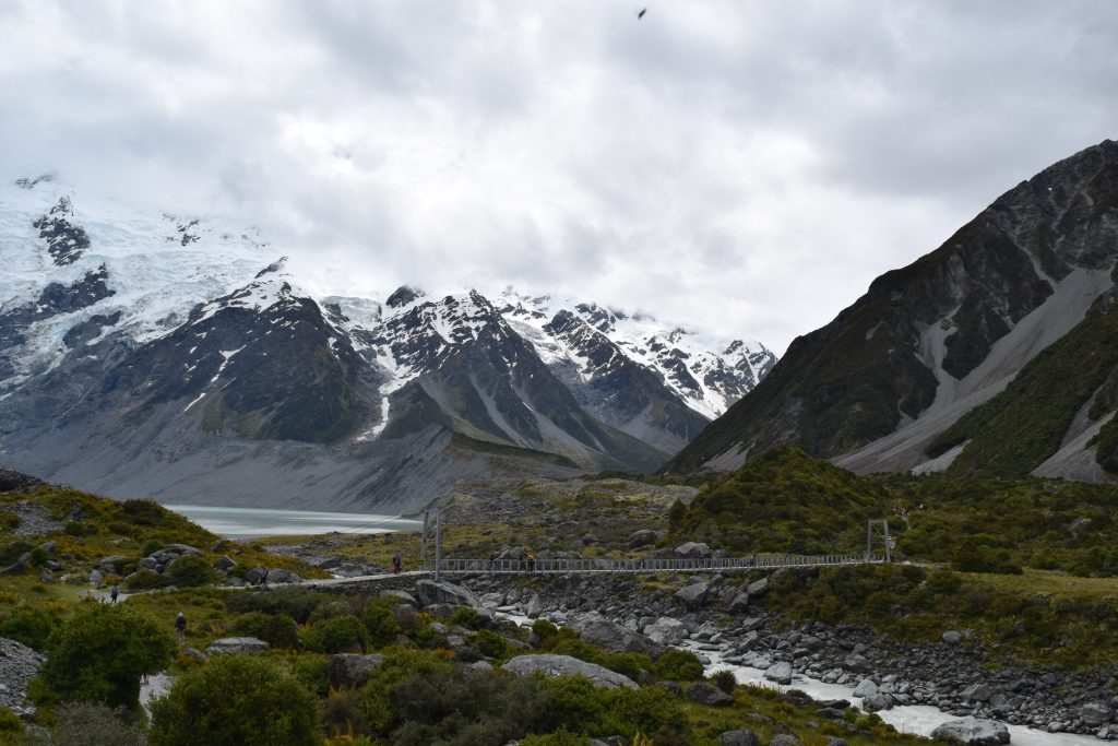 Snow capped mountains with a small bridge along the Hooker Trek in Mt Cook New Zealand