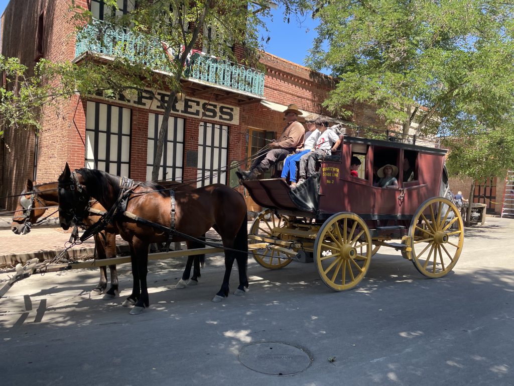 A stage coach with brown horses holding a child at Columbia State Historic Park