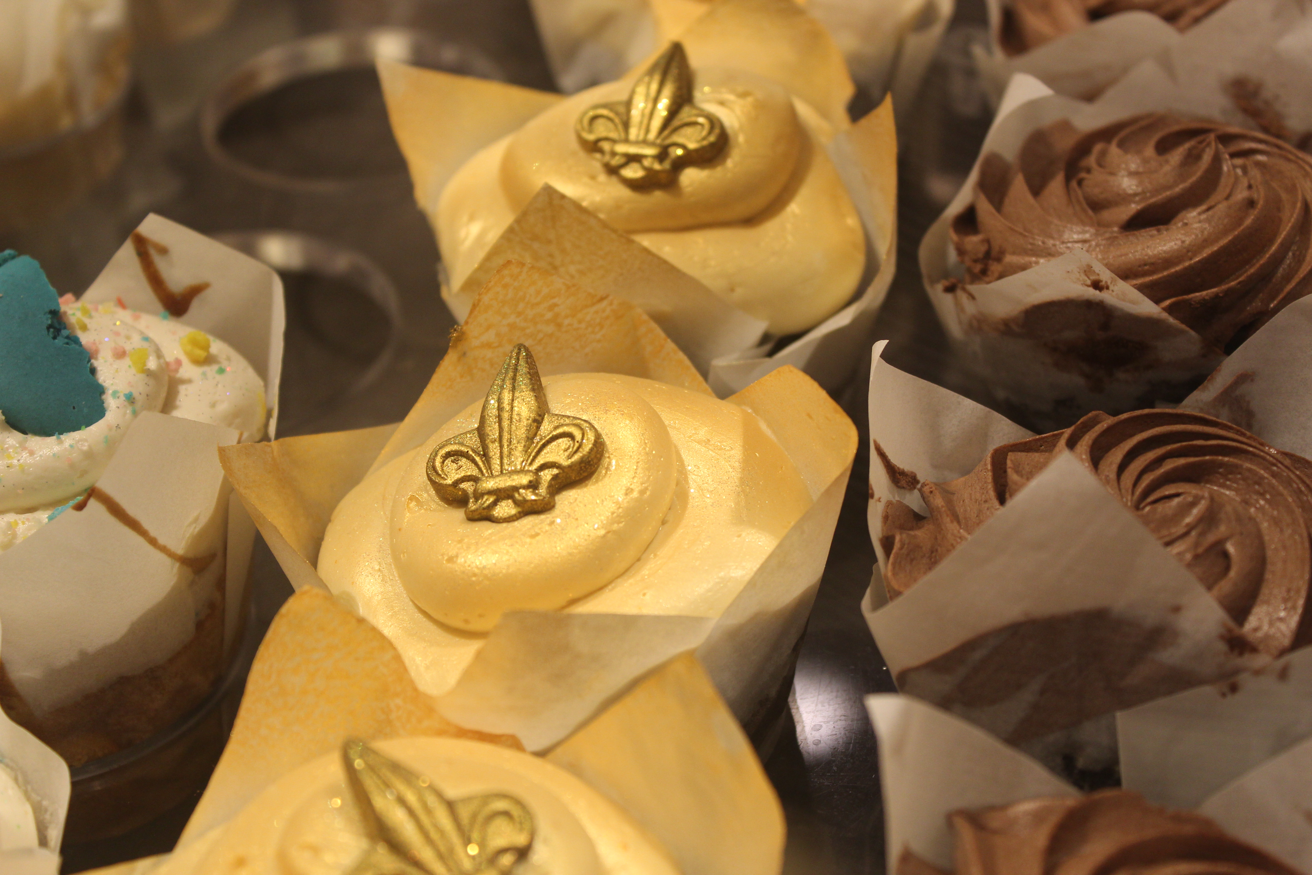 white cupcakes topped with a golden fleur de lis.