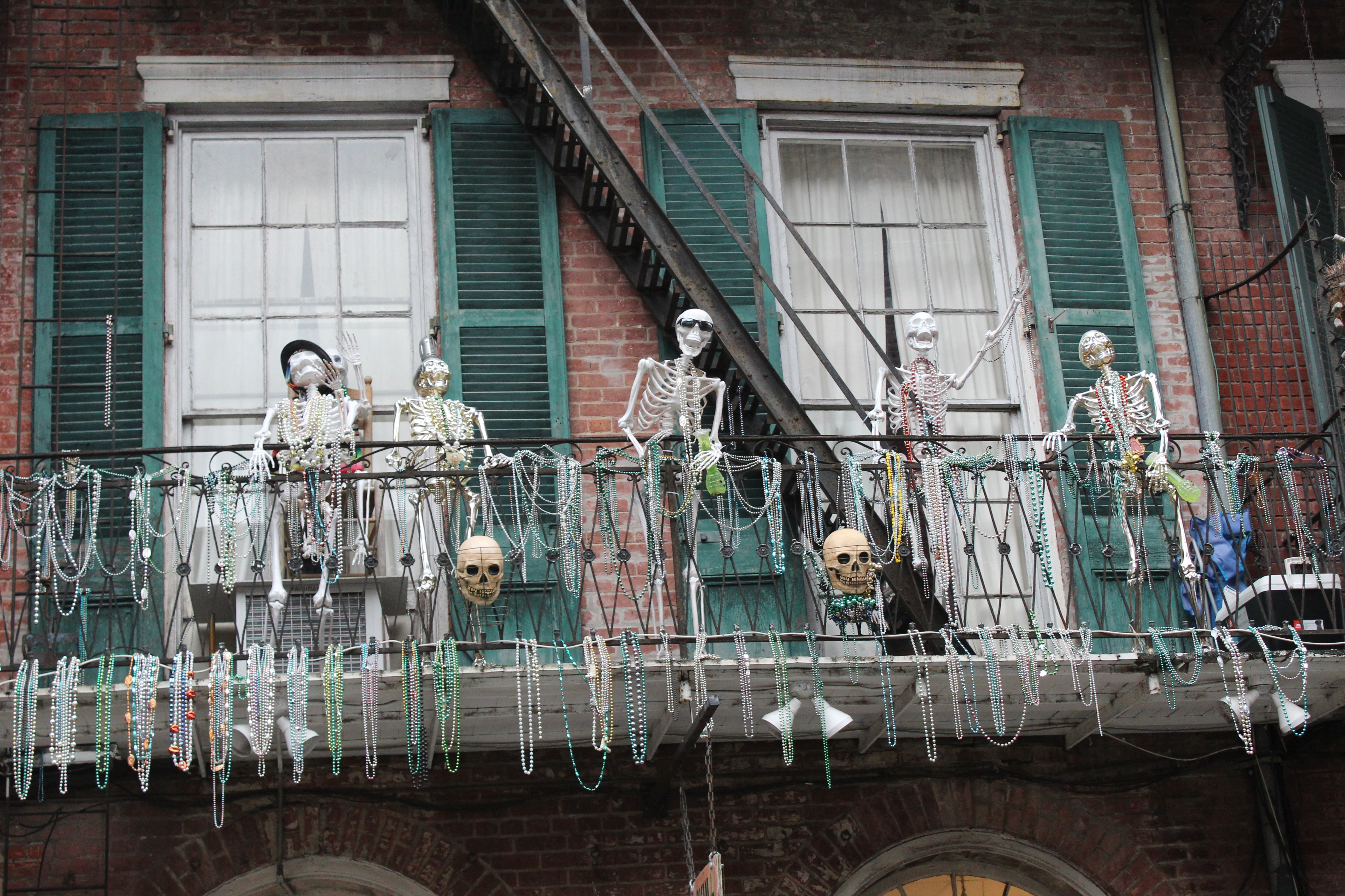 skeletons and mardi gras beads adorn the railing of a balcony