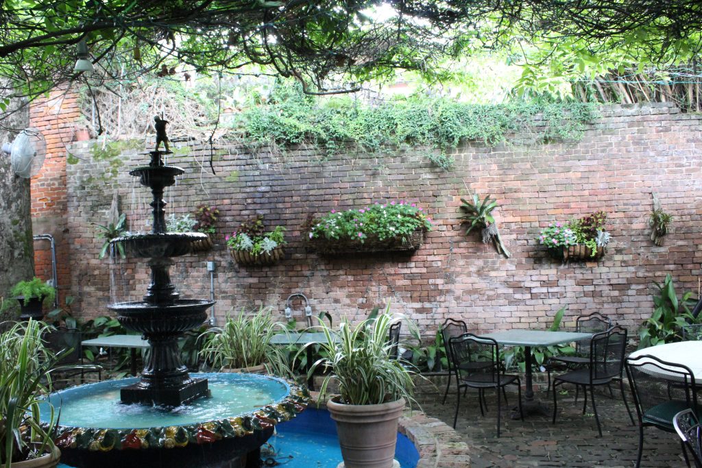 a water fountain set against a brick wall adorned with green plants