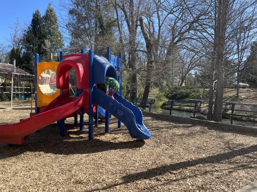 Children's playground with a slide surrounded by trees at Murphys Community Park