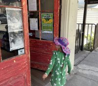 child entering an old red painted door on Main Street in Murphys California