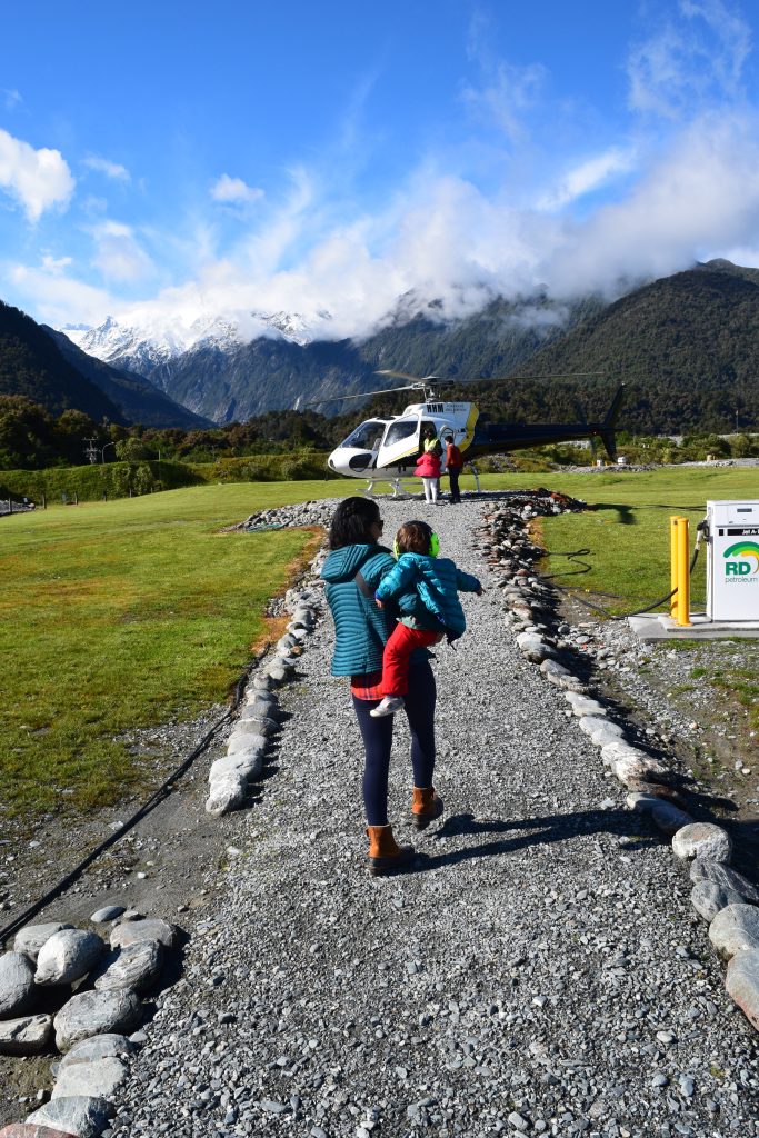 parent and child walking towards a helicopter in Franz Josef New Zealand