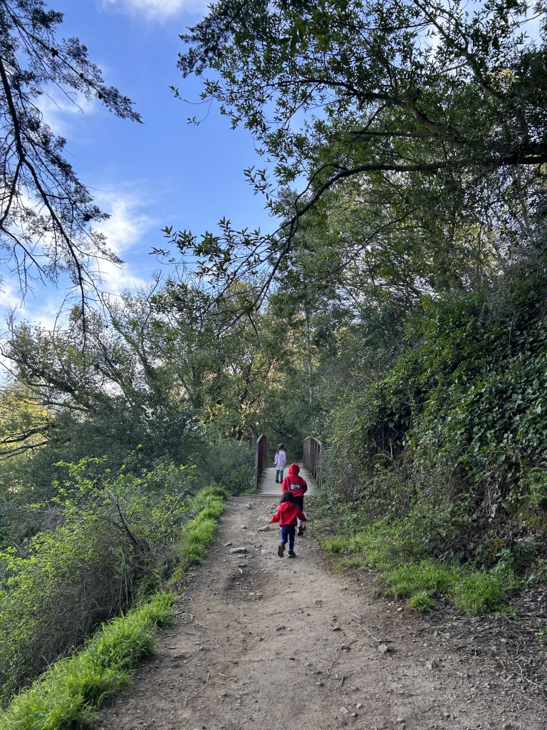Children running along a dirt path on the Bridgeview Troll Trail in Oakland, California