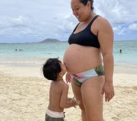 Pregnant person on the beach with older child in Hawaii before a home birth