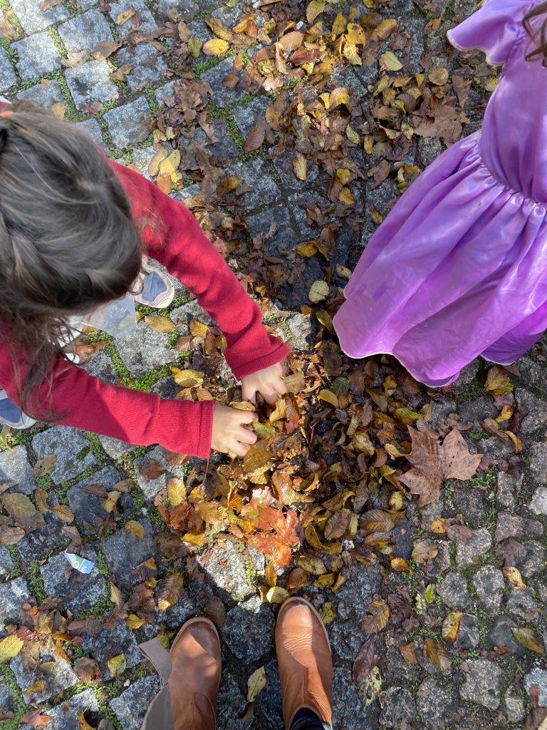 a child in a princess dress playing in leaves on the stone floor of pena Palace in Sintra Portugal