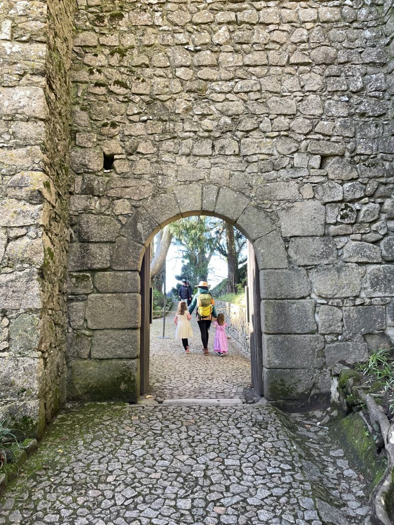 Parent and two children walking through the gate to the Moorish Castle in Sintra Portugal