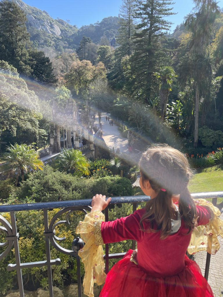 Child in a princess dress looking out on the veranda at Quinta da Regaleira in Sintra, Portugal