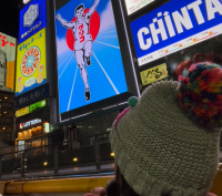 The bright billboards of Dotonbori shine brightly as a child views them from the river.