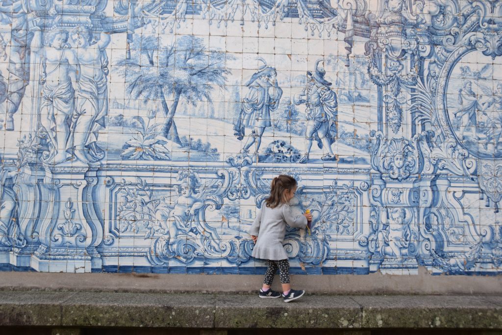 A child in front of blue tiles of Se Cathedral Porto Portugal
