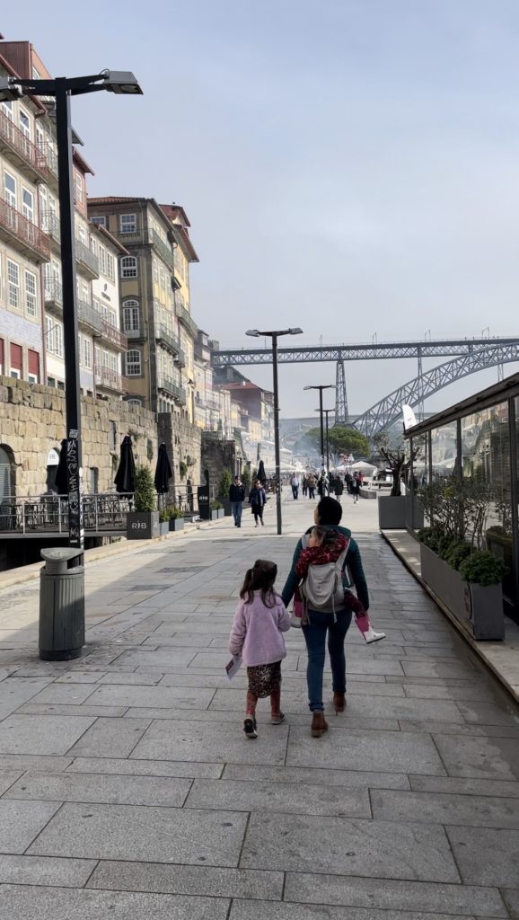 Adult and child walking down Cais da Ribeira in Porto, Portugal in an Ergo