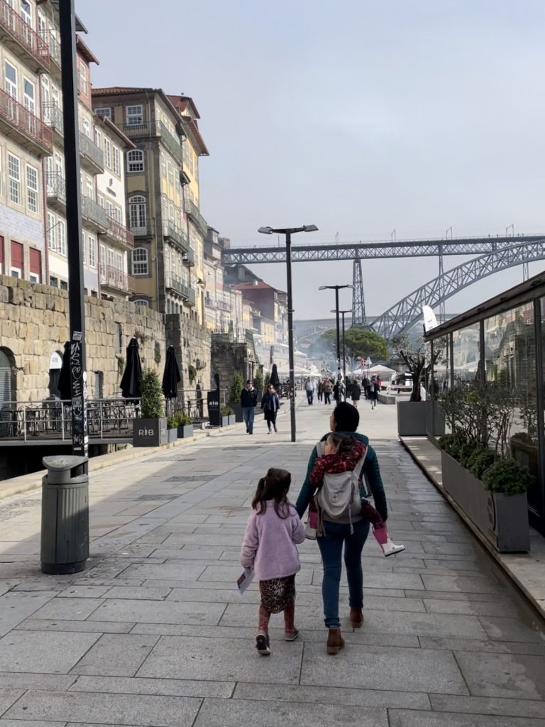 Adult and child walking down Cais da Ribeira in Porto, Portugal in an Ergo