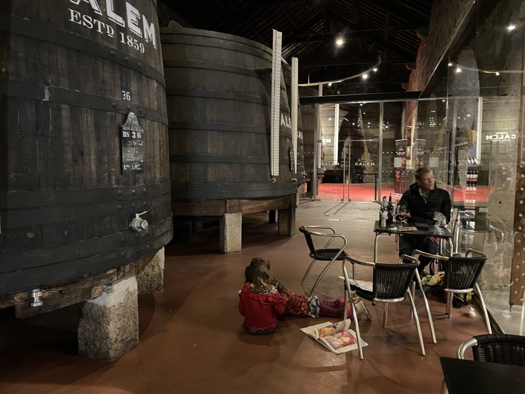 Children playing next to Port wine barrels at Calem Winery in Porto Portugal during a tasting