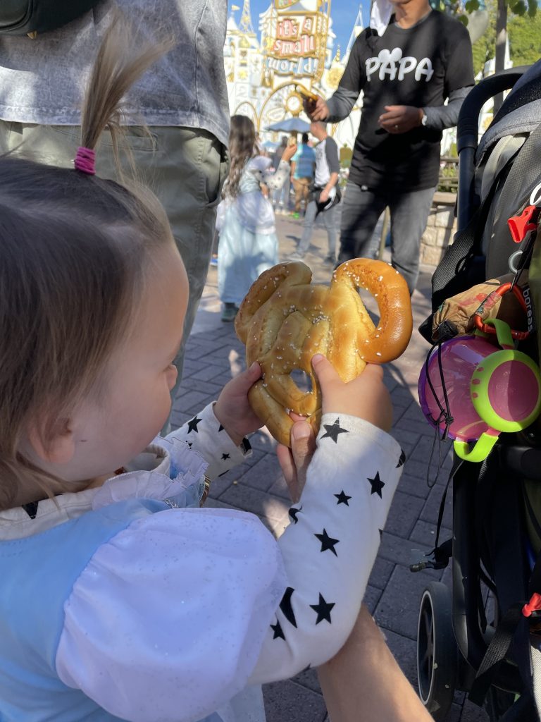 A child holding a Mickey Mouse Pretzel in Disneyland