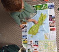 A child standing on top of a map of the South Island of New Zealand