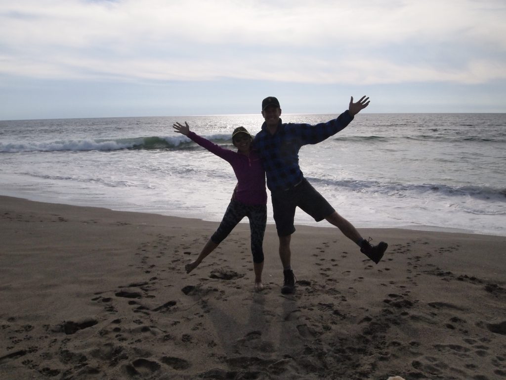 Two adults hugging on the beach in Point Reyes National Seashore